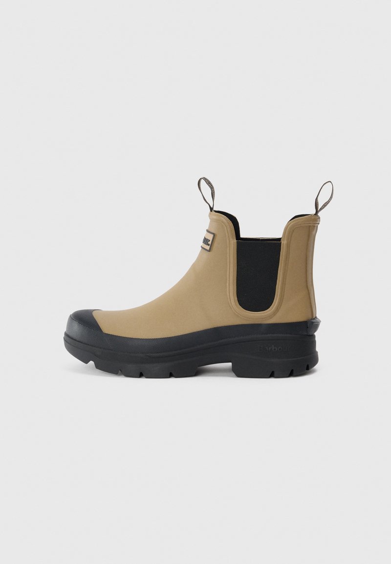 Tan rubber enkelboot met zwarte accenten, treklussen en een gestructureerde zool voor grip. Beschikt over elastische zijpanelen voor gemakkelijk aan- en uittrekken.