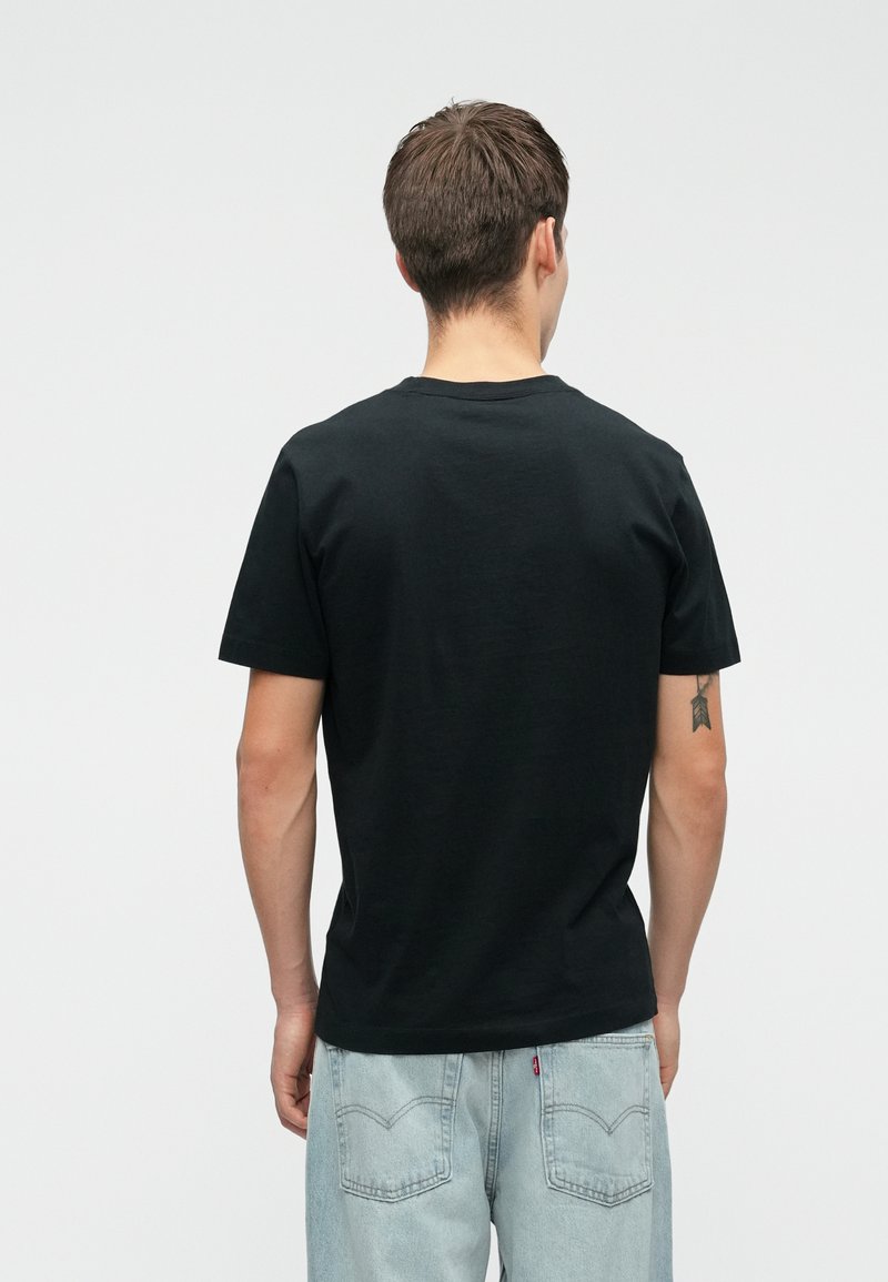 T-shirt noir en coton à manches courtes, avec un col rond et une texture lisse. Pas de graphiques ou de motifs visibles. Coupe décontractée.