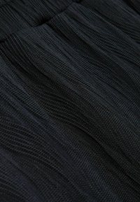 Zwarte textuurstof met een golvend patroon, met een lichte glans en een kreukelige uitstraling, geschikt voor veelzijdige kledingstijlen.