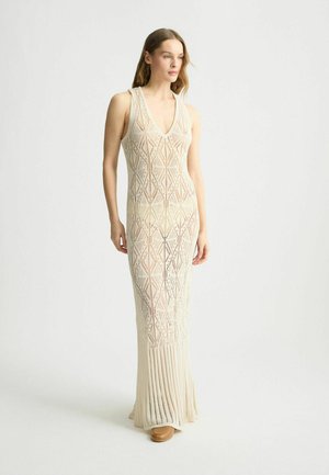 Beige Strick-Maxikleid mit tiefem V-Ausschnitt, das einen gemusterten Oberteil und einen plissierten Rock aufweist. Hergestellt aus leichtem, strukturiertem Material.