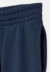 Tummansiniset urheiluhousut, joissa on joustava vyötärö ja sivutaskut. Valmistettu pehmeästä, tekstuurinomaisesta kankaasta, joka tarjoaa mukavan istuvuuden.