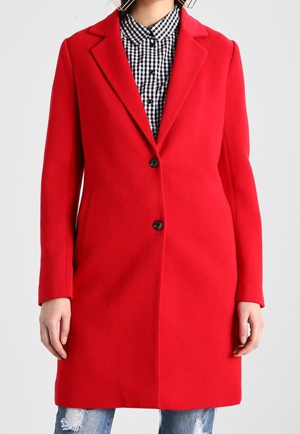 Rød uldblandet frakke med en hakket revers, enkelt knaplukning og forlommer. Båret over en sort-hvid ternet skjorte.