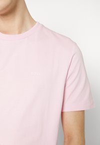 Light pink cotton t-shirt with a crew neckline, short sleeves, and a subtle white "BOSS" logo on the front. Smooth texture.
