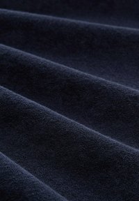 Tissu bleu marine avec une surface douce et texturée, présentant des plis visibles et une texture uniforme dans l'ensemble.