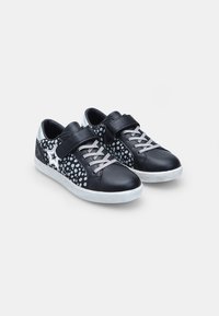 Melnas ādas sporta apavi ar sudraba akcentiem, apļveida punktiņu raksts, lipīgās siksniņas un pelēkas šņores. Baltā gumijas zole.