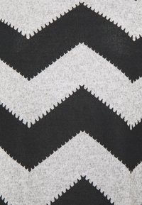 Schwarzer und grauer Stoff mit Chevron-Muster, der eine strukturierte, Zickzack-Optik und eine weiche, gestrickte Oberfläche aufweist. Die Kanten der Chevrons sind gezackt.