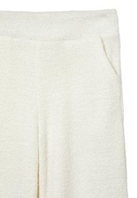 Pantalons en tissu blanc texturé, avec une large ceinture élastique et des poches latérales. Le matériau a une apparence douce et tissée.