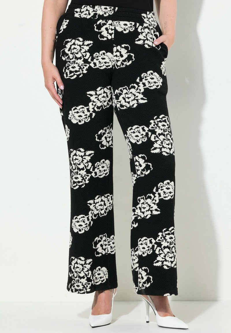 Zwarte bloemenpatroon broeken met een textuurafwerking; witte bloemen; wijde pijpen; zakken; gecombineerd met witte hoge hakken.