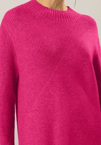 Maglione rosa a maglia caratterizzato da un colletto a costine, un motivo testurizzato diagonale e una finitura morbida. Il tessuto è spesso con dettagli superficiali variabili.