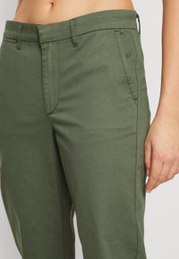Khaki-green trousers with a fitted waist, two side pockets, and straight-cut legs. The fabric appears smooth with a clean finish.
