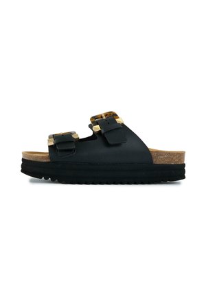 Black slide sandal with thick sole, cork footbed, and two adjustable tortoiseshell buckled straps across the top.