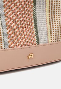 Borsa in tessuto intrecciato con base in pelle rosa. Presenta un design testurizzato in colori terra, con un accento in oro sul settore inferiore.