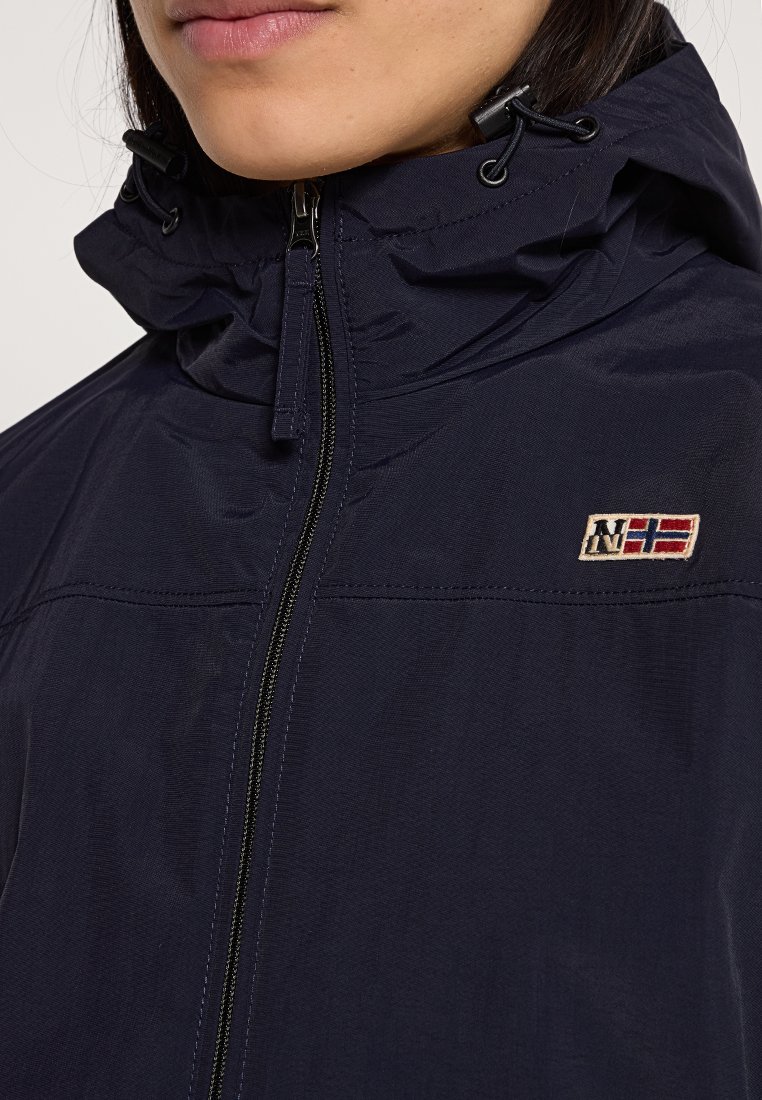 Giacca a vento blu navy con colletto alto, chiusura con zip e cappuccio regolabile. Presenta un piccolo logo ricamato sul petto.