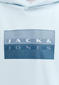 Sweat à capuche bleu clair avec un logo rectangulaire affichant le texte "JACK & JONES" en lettres majuscules.
