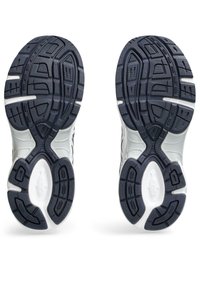 Valkoiset ja laivastonsiniset urheilukenkien pohjat, joissa on teksturoitu kumipinta, monisuuntaiset urasyntyiset ja vaimennuselementit pidon ja tuen vuoksi.