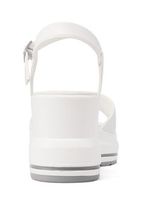 Sandali bianchi con una suola spessa e ammortizzata, cinturino alla caviglia regolabile e dettagli testurizzati nel tallone. Design pulito e minimale.