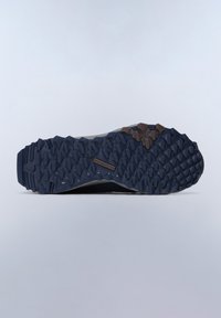 Suola di scarpa atletica nera e grigia con un motivo in gomma testurizzata, caratterizzata da scanalature prominenti e un dettaglio accentato marrone sul tallone.