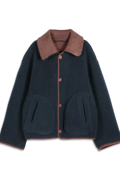 Veste polaire bleu marine avec col marron, fermeture par boutons, deux grandes poches avant, et bordure marron sur les bords et les poignets.