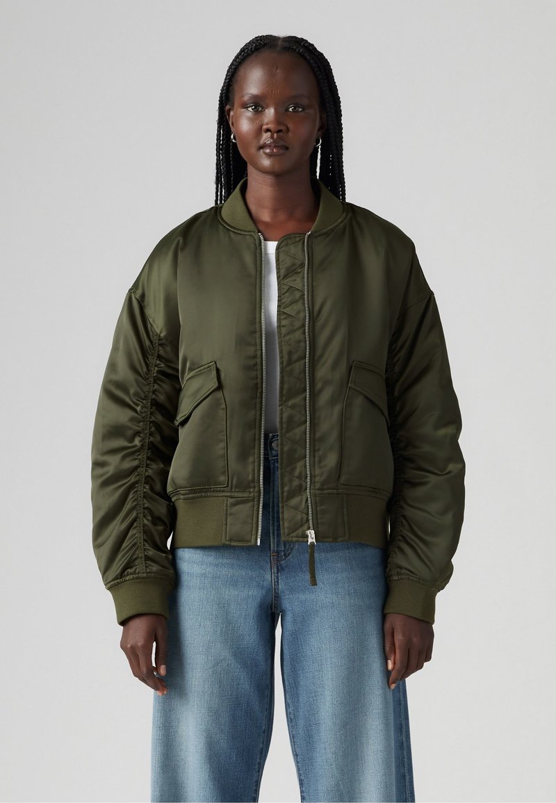 Olive green bomber jacket with a zip front, ribbed cuffs, and two front pockets. Smooth satin texture with a cropped design.