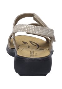 Jasno beżowe sandały z teksturowaną cholewką, regulowanymi paskami i wyściełanym wkładką. Posiadają czarną podeszwę zewnętrzną i subtelnym wzorem liści wewnątrz.