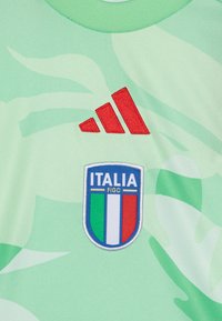 Maillot de sport vert avec une finition texturée. Comprend le logo rouge d'Adidas et l'emblème national de l'Italie brodé avec des couleurs bleu, blanc et rouge.