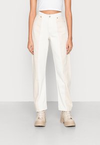 Höga byxor i en ljus beige och vit colorblock-design, med rak passform, knappstängning och sidofickor.