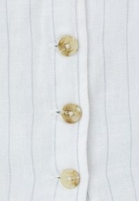 White linen fabric with light blue vertical stripes, featuring three round, light brown buttons stitched at the center.
