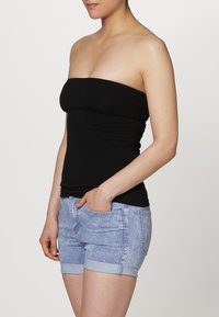 Zwarte strapless top met een glad en aansluitend ontwerp, gecombineerd met lichtblauwe denim shorts met omgeslagen zomen en voorzakken.