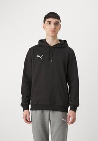 Zwarte hoodie met een kangoeroezak, voorzien van een klein wit Puma-logo op de linkerborst. Gemaakt van zacht materiaal, met een ontspannen pasvorm.