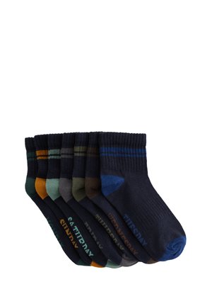 Sieben Paare dunkel gefärbter Knöchelsocken mit verschiedenfarbigen Fersen und Zehen, jeweils mit einem Wochentagnamen von Sonntag bis Samstag beschriftet.