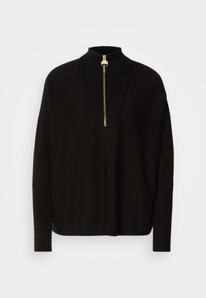 Černý svetr s vysokým límcem, polozipem a žebrovanými detaily. Má dlouhé rukávy a volný střih se rovnými lemy.