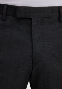 Grijze textuurige broek met een platte voorkant, geweven stof en verstelbare tailleband; voorzien van scherpe plooien en subtiel ruitpatroon.