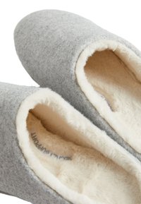 Grijze gevoelslippers met een zachte witte nepfur voering, ronde neus en flexibele constructie. Het interieur toont labels op de textiel.