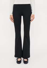 Zwarte flare broek gemaakt van stretchstof, met een aansluitende taille, een soepele textuur en een strakke, moderne uitstraling.