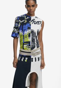 Mehrfarbiges grafisches Kleid mit einem Halbarm-Design, Textilmustern, einem seitlichen Schlitz und einem kontrastierenden Gürtel in neutraler Farbe.