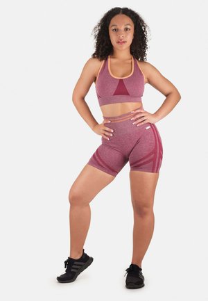 Set di reggiseno sportivo e pantaloni corti color bordeaux con accenti arancioni a contrasto, caratterizzato da una finitura testurizzata e modelli geometrici sui pantaloni.