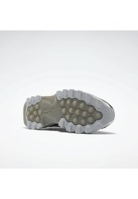 Schuhsohle mit einer grauen Gummisohle, die mit strukturierten Mustern und runden Erhebungen für Trittsicherheit versehen ist, geformt für Flexibilität und Stabilität.