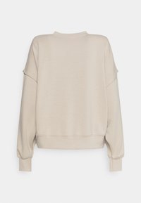 Sweat-shirt beige à manches longues avec épaules tombantes, poignets côtelés et ourlet côtelé, présenté de dos sur un fond uni.