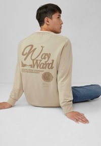 Beige crewneck sweatshirt met een grote bruine grafische print op de achterkant, inclusief tekst en natuurfotografie; geribde manchetten, losse pasvorm.