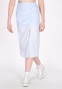 Lichtblauwe midi-rok met gerimpelde textuur, geborduurde bloemenpatronen en een split aan de voorkant. Gecombineerd met witte hoge sneakers.