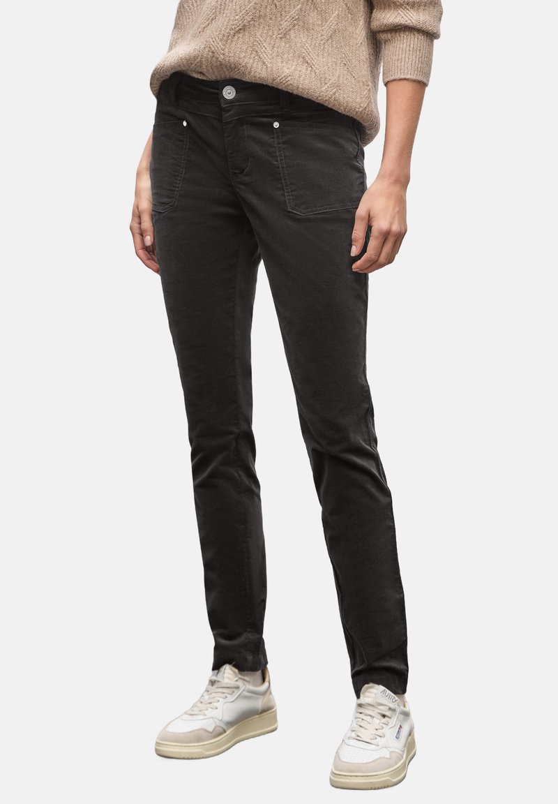 Černé slim-fit kalhoty vyrobené z bavlněné směsi, s předními kapsami, zapínáním na knoflík a jemnou strukturou. V kombinaci s bílými teniskami.