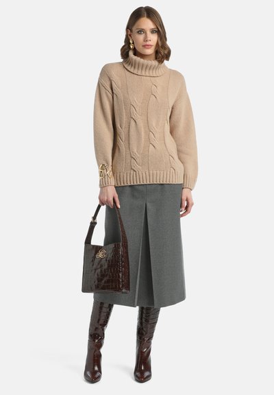 Beige kabelstickad tröja med hög krage, grå plisserad kjol och mörkbrun läderväska med krokodilpr Prägel. Bruna knähöga stövlar.