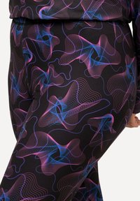 Leggings in tessuto elasticizzato con una base nera, caratterizzati da vivaci modelli astratti a onde rosa e blu, che creano una texture visivamente dinamica.