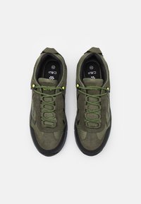 Grüne Wildledersneaker mit schwarzen Gummisohlen, strukturierten Einsätzen und leuchtend grünen Schnürsenkeln. Merkmale sind schwarze Chevron-Akzente an den Seiten. Größe 42.