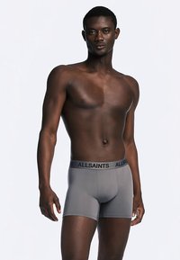 Boxer grigi con fascia in vita nera con logo "ALLSAINTS", caratterizzati da una texture liscia del tessuto e un design aderente.