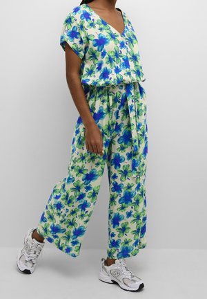 Kombinezon w kwiaty w zielono-niebieskich odcieniach, z krótkimi rękawami, dekoltem w serek, paskiem w talii i szerokimi nogawkami. Połączony z białymi trampkami.