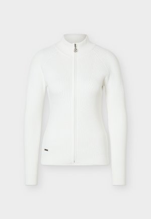 Jachetă albă tricotată cu nervuri, mâneci lungi, fermoar frontal complet și guler ridicat, siluetă ajustată și logo mic metalic aproape de tiv.