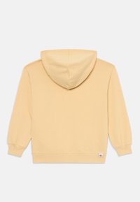 Sweat-shirt à capuche beige clair posé à plat, montrant le dos avec des manches longues et une petite étiquette près de l'ourlet sur un fond blanc.