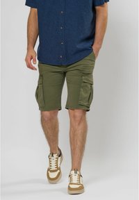 Groene cargoshorts met meerdere zijzakken, van katoen en met een rechte pasvorm, gecombineerd met crèmekleurige en bruine schoenen en een blauwe blouse.