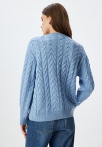 Maglione azzurro chiaro a lavorazione cable-knit con un motivo testurizzato, polsini e orlo ribattuti. Presenta una vestibilità comoda e un tessuto morbido.